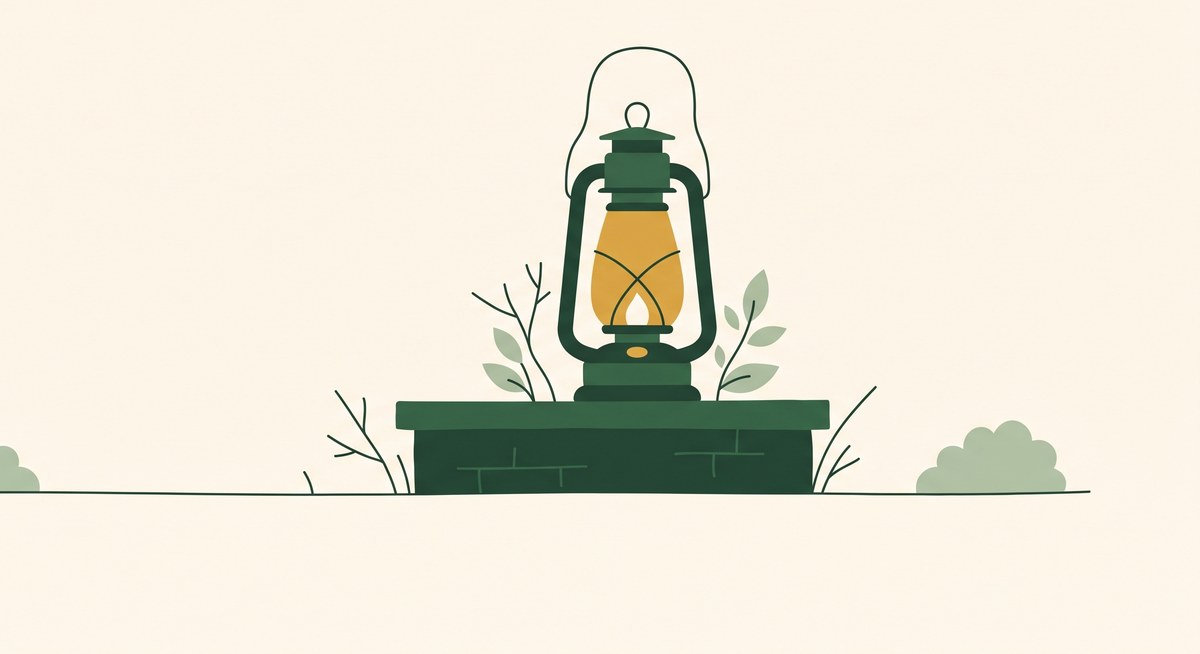 A lantern glowing on a low garden wall